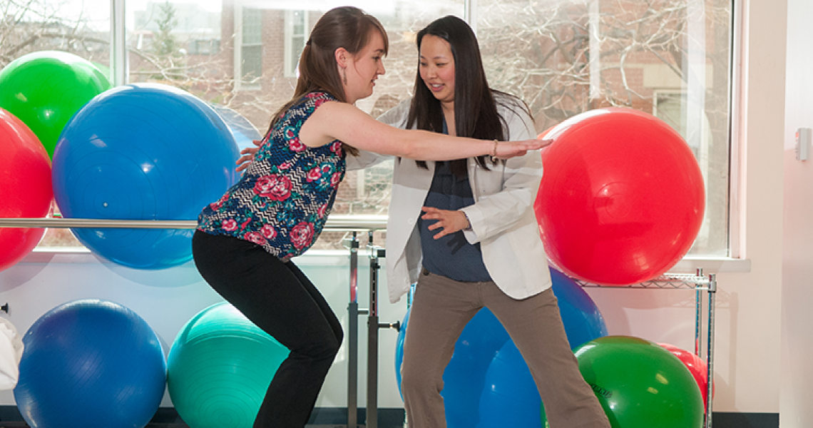 Physical therapist in a clinic working with a patient with exercise balls in view