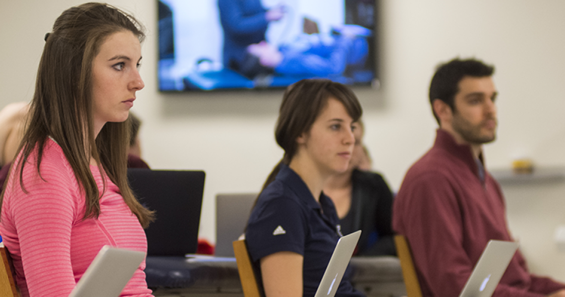 Students sitting in a lecture room in front of laptops