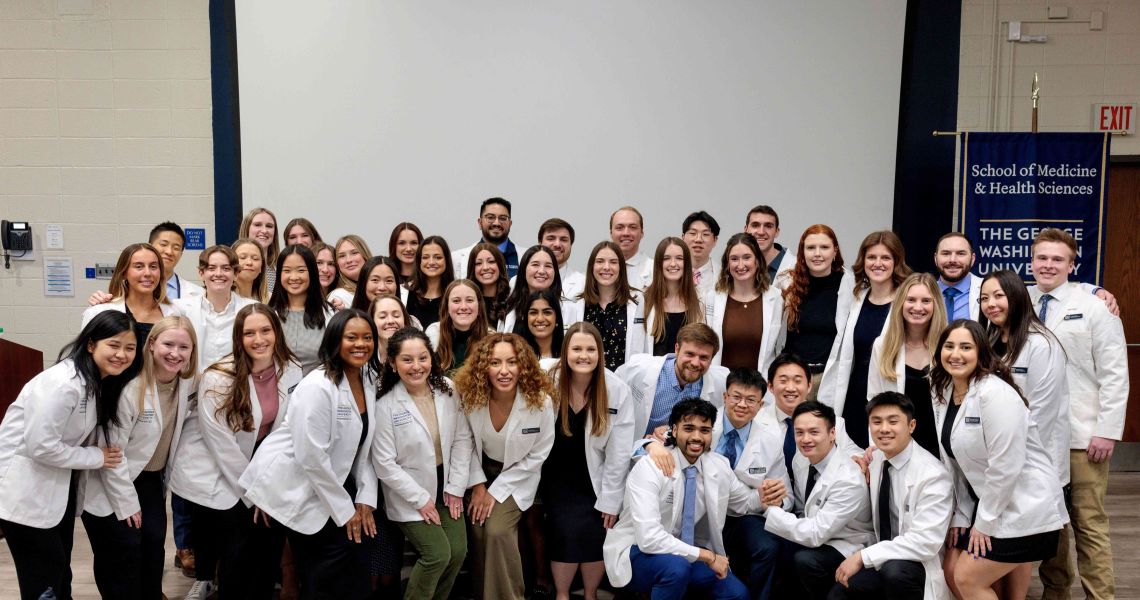 DPT students in white coats pose for group photograph