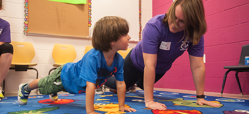 PT student doing a pushup next to a child