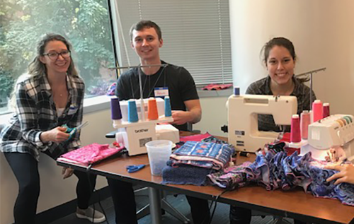 Alumni sitting at a table with a sewing machine