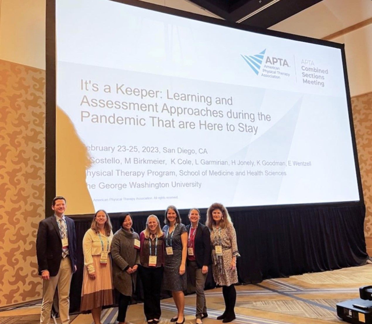 Faculty members Cole, Wenzell, Birkmeier, Goodman, Jonely, Garmirian and Costello pose in front of presentation screen at CSM
