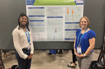 two women standing in front of a poster of a scientific study