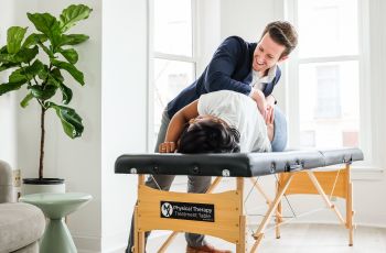 Alumni Josh D'Angelo treating patient on treatment table in sunlit room